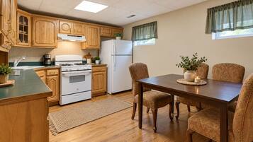 Una cocina con armarios de madera, estufa, refrigerador y mesa de comedor con sillas.