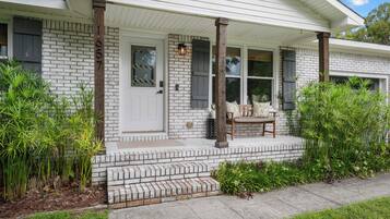 A house with a brick facade, a white door, and a porch with a bench.