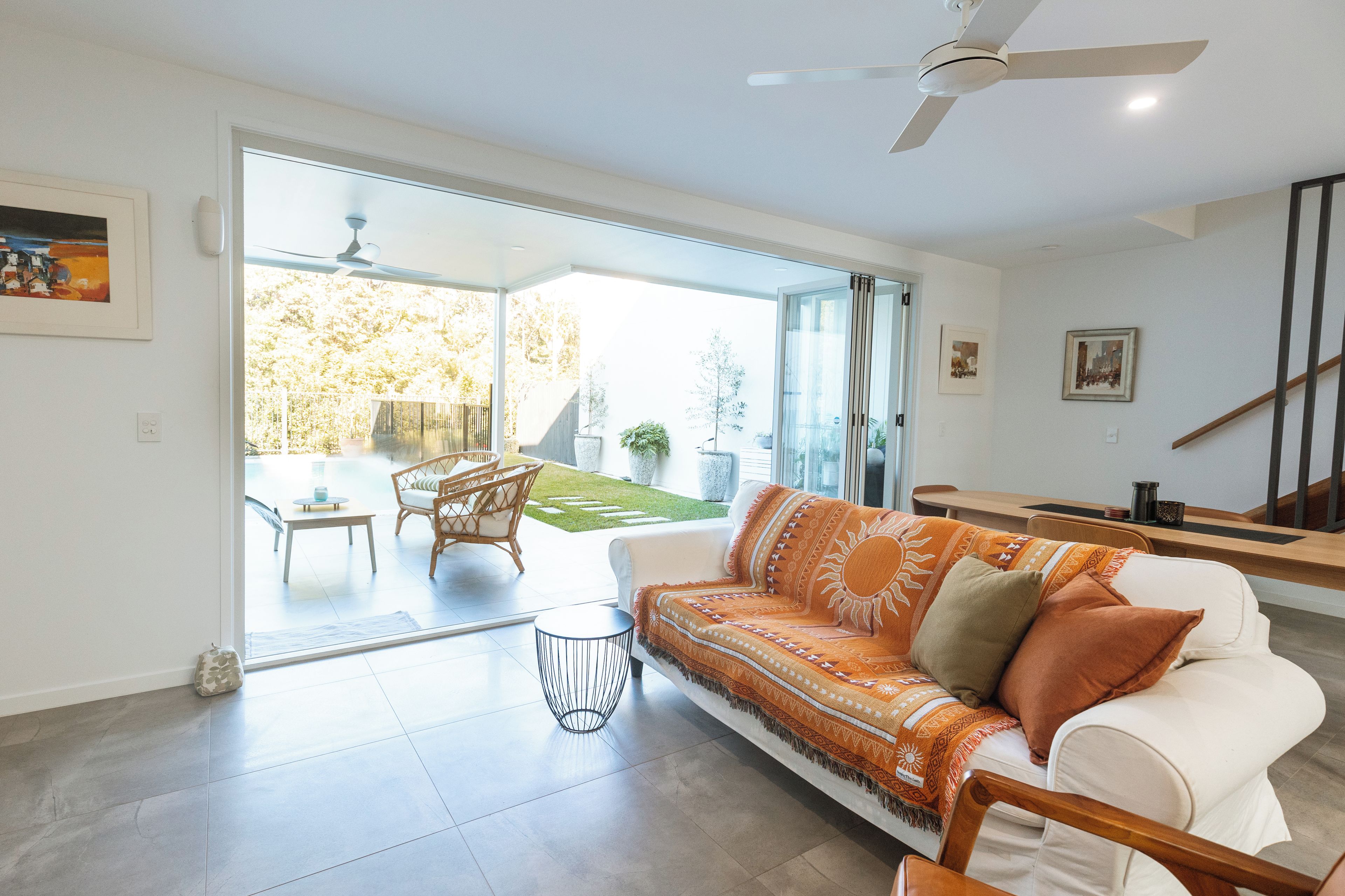 Un salon moderne avec un canapé blanc, une table basse et un coin repas avec des chaises.