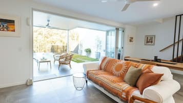 Un salon moderne avec un canapé blanc, une table basse et un coin repas avec des chaises.
