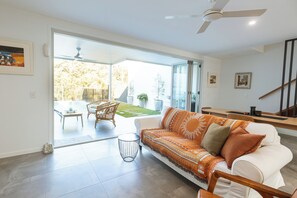 Un salon moderne avec un canapé blanc, une table basse et un coin repas avec des chaises.