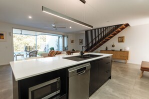 A modern kitchen with a central island, built-in dishwasher, and a stainless steel oven.
