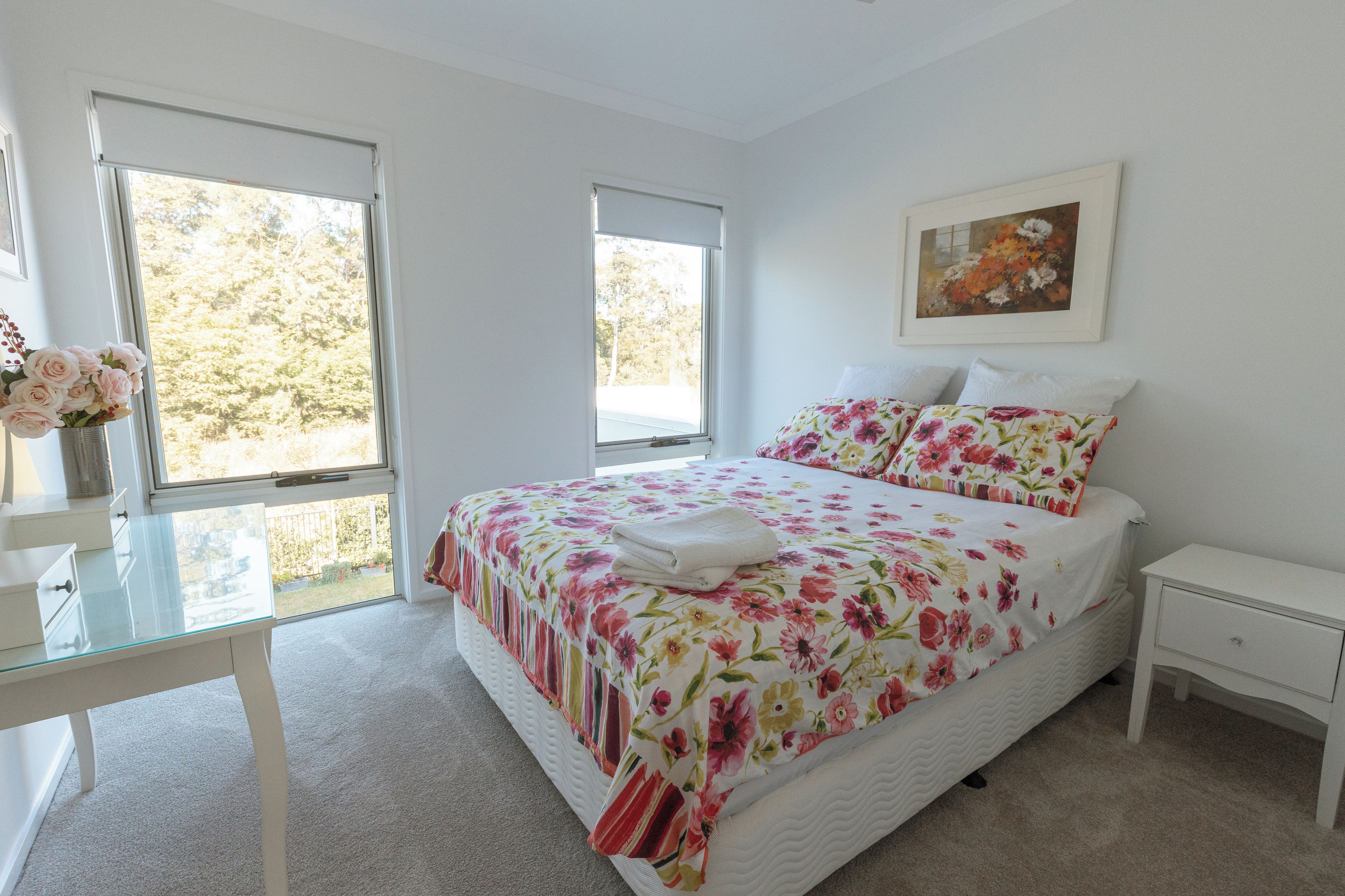 Un dormitorio con una cama, una mesita de noche, una silla y un ventanal.