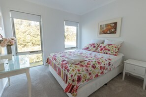 Une chambre à coucher avec un lit, une table de chevet, une chaise et une fenêtre.