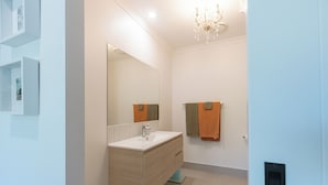 Uma casa de banho moderna com um espelho grande, uma pia e um porta-toalhas.