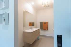 Une salle de bain moderne avec un grand miroir, un lavabo et un porte-serviettes.