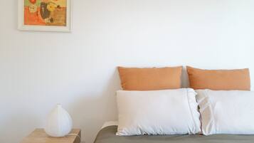 Ein Schlafzimmer mit einem Bett, Kissen, einem Nachttisch, einer Lampe und einem Bild an der Wand.