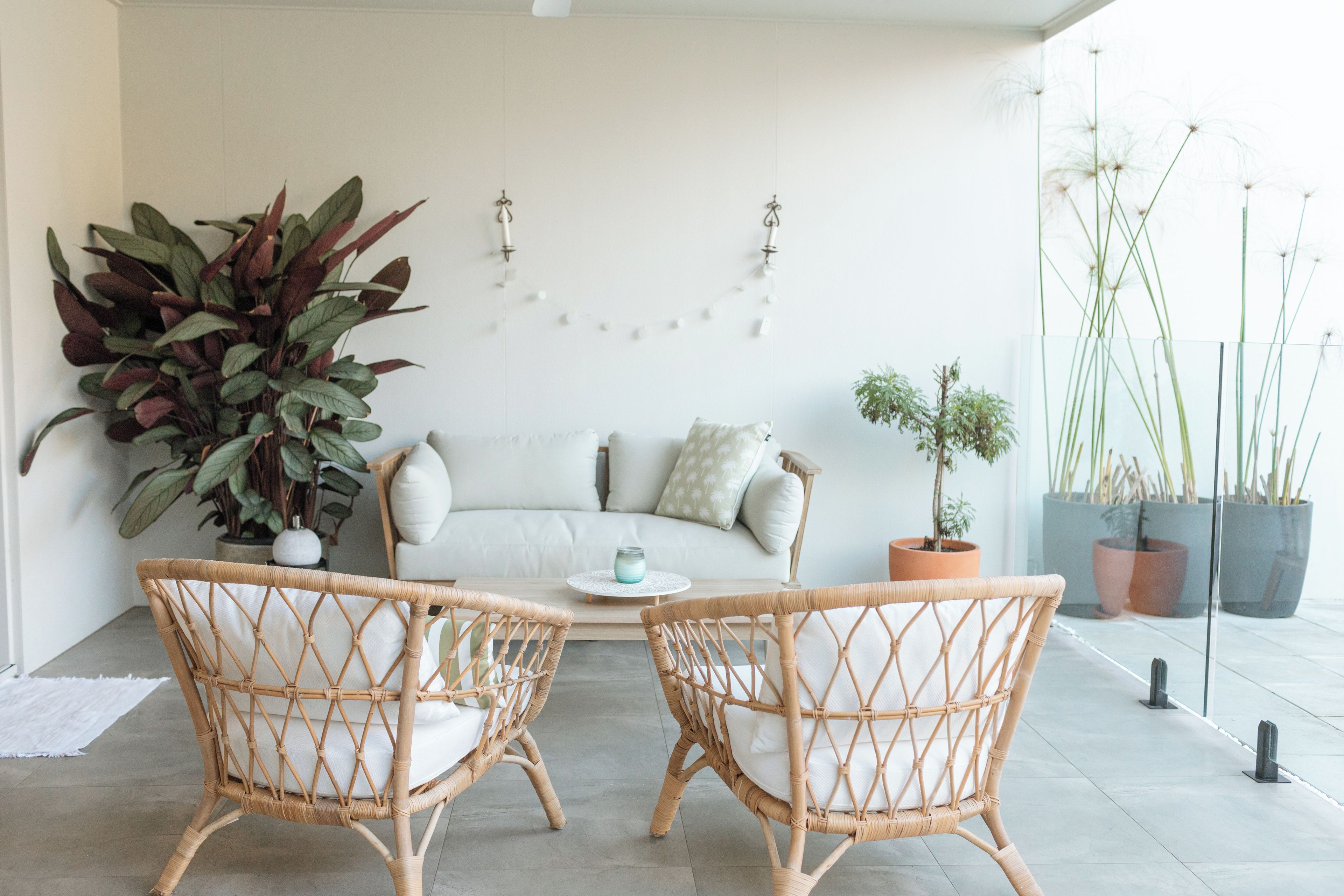 A modern living room with a sofa, two wicker chairs, and a coffee table.