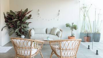 A modern living room with a sofa, two wicker chairs, and a coffee table.
