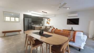 Una cocina moderna con refrigerador, estufa y comedor con mesa y sillas.