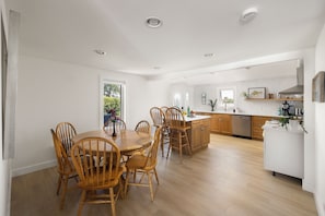 Une cuisine moderne avec des meubles en bois, un îlot central et un coin repas comprenant une table ronde et des chaises.