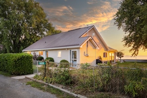 Une maison de plain-pied avec un toit à pignon, un porche à l’avant et une cour clôturée.