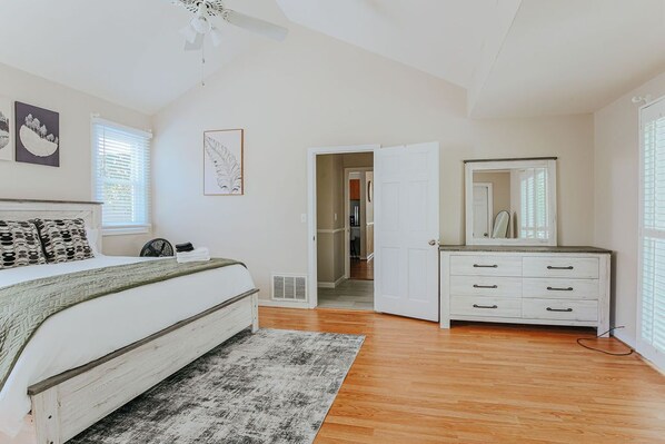 Un dormitorio con cama, mesita de noche, cómoda y vestidor.