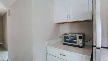 A kitchen with white cabinets, a built-in toaster oven, and a stainless steel refrigerator.