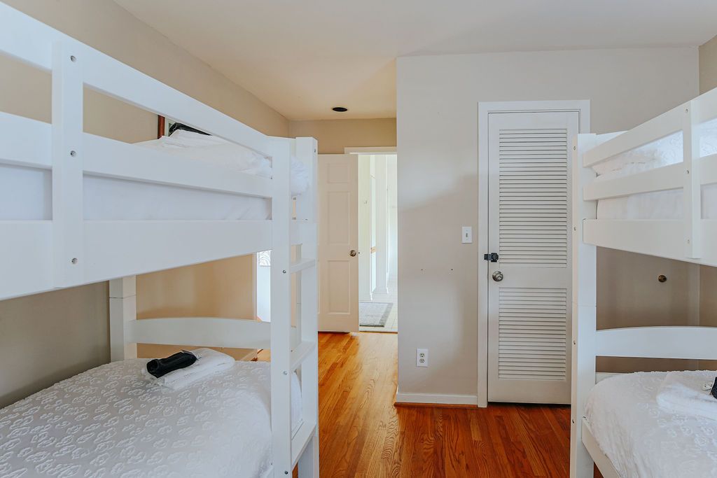 Una habitación con literas, una puerta y un pasillo que conduce a otra estancia.