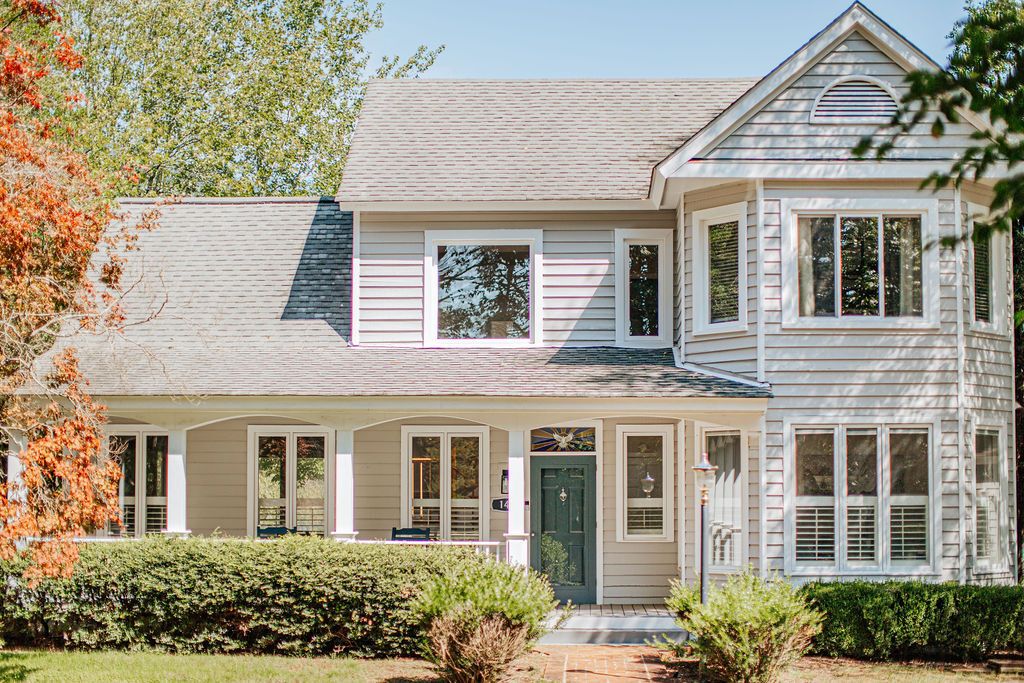 A two-story house with a front porch, a green door, and a small front yard.