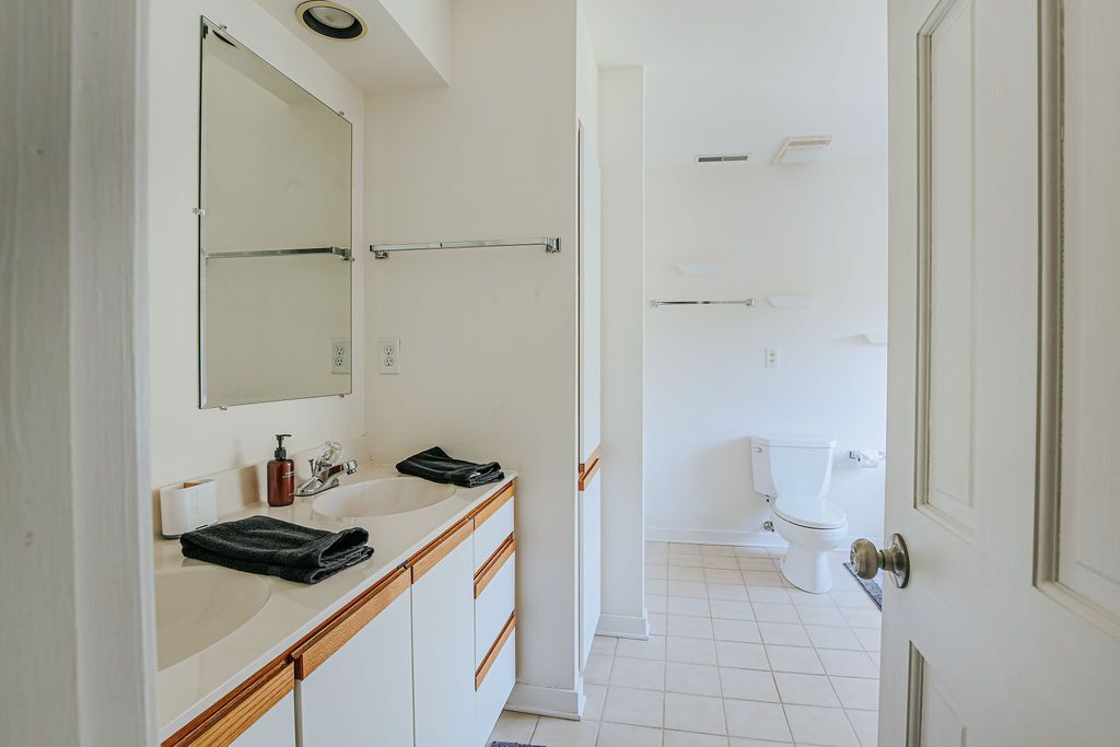 Un baño con lavabo blanco, espejo y retrete.