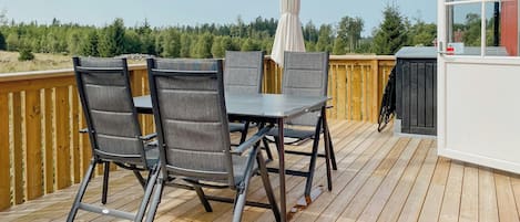 A deck with a table and chairs, an umbrella, and a view of trees.