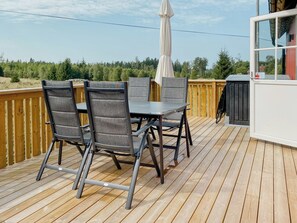 A deck with a table and chairs, an umbrella, and a view of trees. - Secluded nature retreat with sauna near Ullared (Fegen)