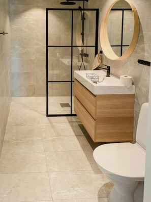 A modern bathroom with a glass shower enclosure, a wooden vanity, and a round mirror. - Secluded nature retreat with sauna near Ullared (Fegen)