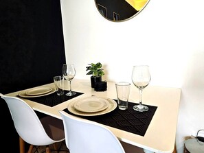 A dining table set with plates, glasses, and a small potted plant. - Trendy Studio Near 5th Ave & Beach | Rooftop Pool (Playa del Carmen)