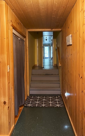 A wooden interior hallway with a staircase leading to a door marked 'Exit.'
