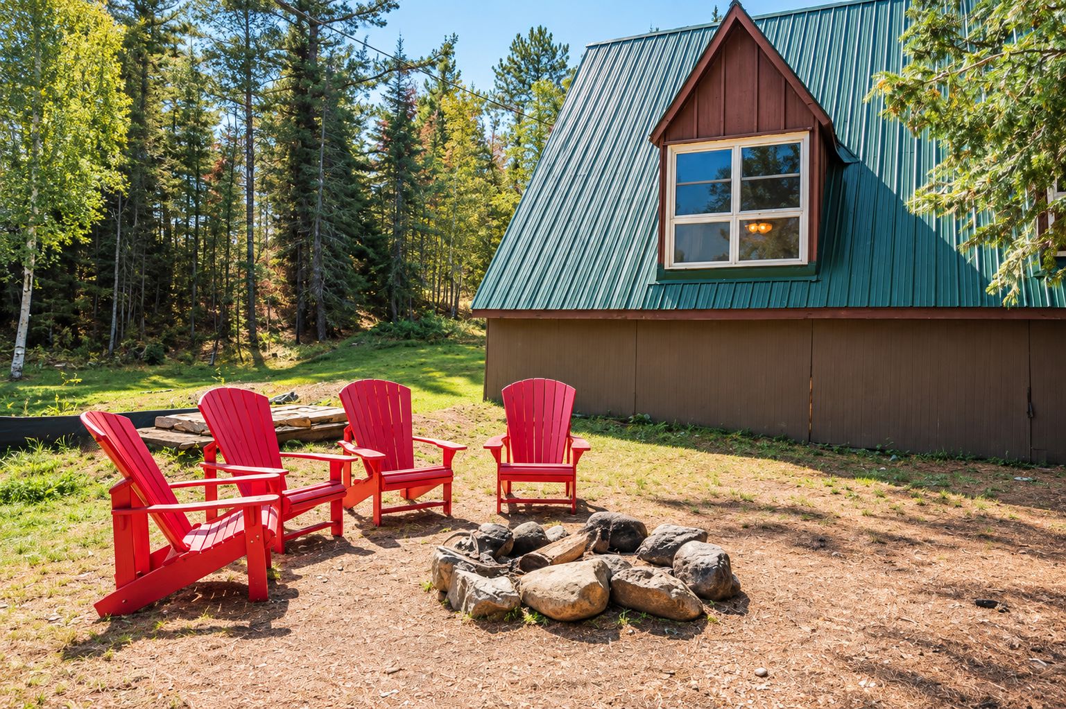 Une cabane avec un toit végétalisé, un revêtement extérieur en bois et un petit porche agrémenté de chaises Adirondack rouges.