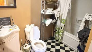 Une salle de bain avec un carrelage à motifs géométriques, des toilettes, un lavabo et un rideau de douche.