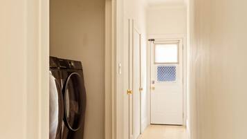 A laundry room with a washing machine and dryer, a white door with a window, and a wooden floor.