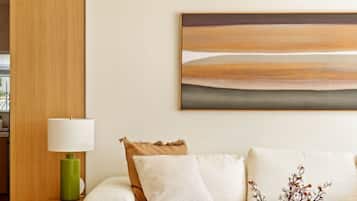 A modern living room with a sofa, a coffee table, a lamp, and a painting on the wall.