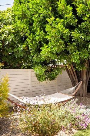 A hammock under a tree in a garden with a wooden fence and flowering plants. - Westchester LA 4BR/4BA Home | Silicon Beach (Culver City)