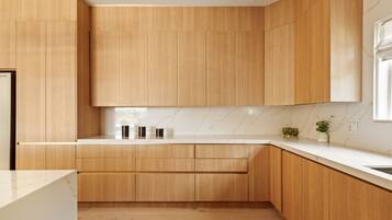 A modern kitchen with wooden cabinets, a marble countertop, and a small plant on the counter.