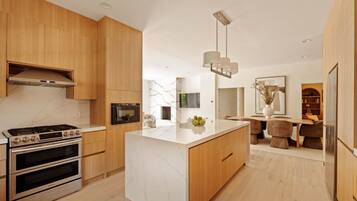 A modern kitchen with a central island, built-in ovens, and wooden cabinetry.