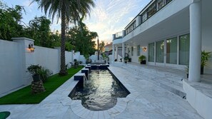 A modern outdoor pool area with a water feature, surrounded by a white building with large windows and a balcony. - Four bedroom  in United States of America, Lutz (Lutz)