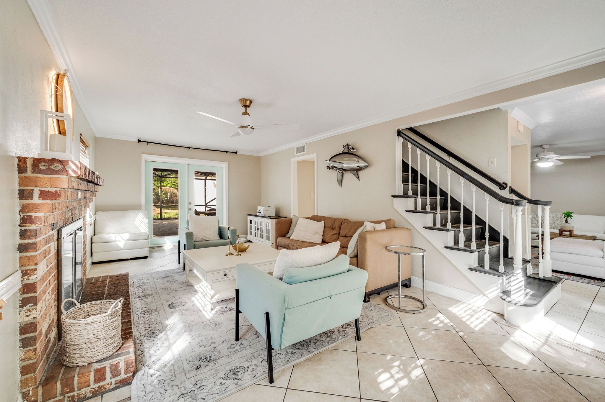A spacious living room with a fireplace, a staircase, and a view of the outdoors.