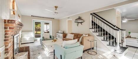 A spacious living room with a fireplace, a staircase, and a view of the outdoors.
