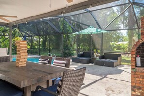 Un patio techado al aire libre con piscina, mobiliario y zona de barbacoa.