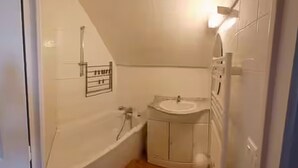 Une petite salle de bain avec une baignoire, un lavabo et des toilettes.
