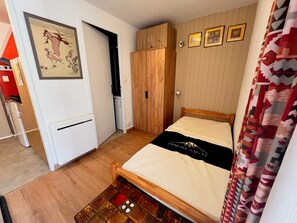 Ein Schlafzimmer mit einem Bett, einem Kleiderschrank, einer Heizung und einer Wand mit gerahmten Bildern.