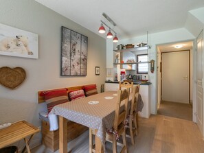 A cozy dining area with a wooden table and chairs, a heart-shaped wall decoration, and a painting above the table. - Semi-detached chalet south, shuttle to slope - 7 guests (La Salle-les-Alpes)