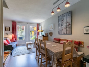 Una habitación acogedora con una mesa de comedor, sillas, un sofá y una televisión.