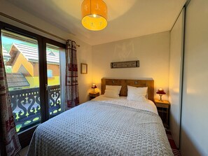 A bedroom with a bed, two bedside tables with lamps, a window with curtains, and a wall-mounted picture. - Semi-detached chalet south, shuttle to slope - 7 guests (La Salle-les-Alpes)