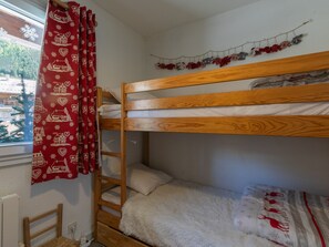 A bunk bed with a ladder, a window with a view of trees, and a red curtain with a pattern. - Semi-detached chalet south, shuttle to slope - 7 guests (La Salle-les-Alpes)