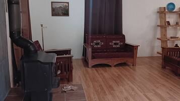 A living room with a fireplace, wooden furniture, a tiled floor, and a wall-mounted shelf.