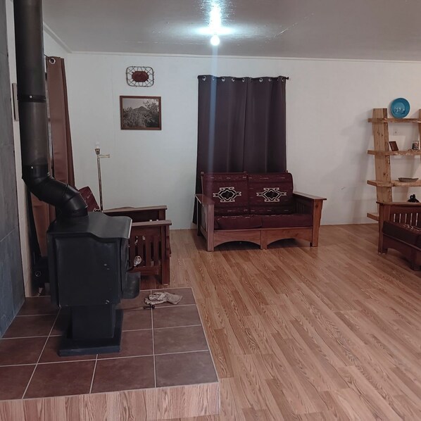 A living room with a fireplace, wooden furniture, a tiled floor, and a wall-mounted shelf.