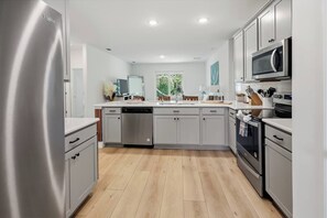 Eine moderne Küche mit Edelstahlgeräten, grauen Schränken und Holzboden.