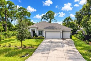 A single-story house with a garage, surrounded by a well-maintained lawn and trees. - Boater’s Retreat | 4BR Home Near the Beach (Sebastian)