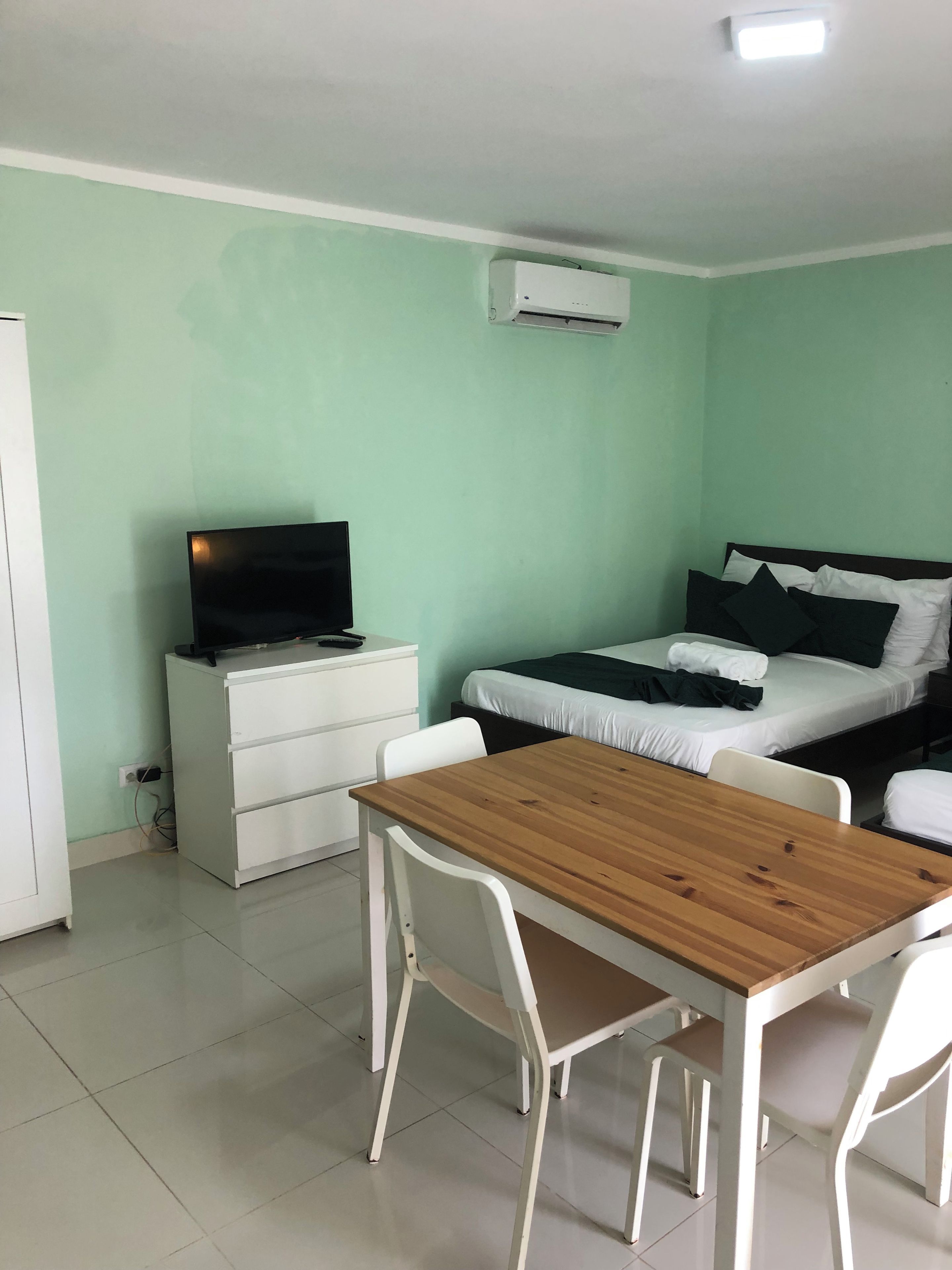 Una habitación con cama, escritorio, silla y televisor.