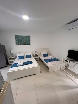 A hotel room with two beds, a TV, a desk, and a painting on the wall. - Sol Caribe Tropical Beach Suites (Punta Cana)