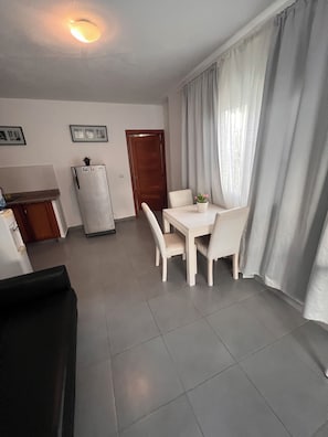 A dining area with a table and chairs, a refrigerator, and a door in a residential setting. - Sol Caribe Tropical Beach Suites (Punta Cana)
